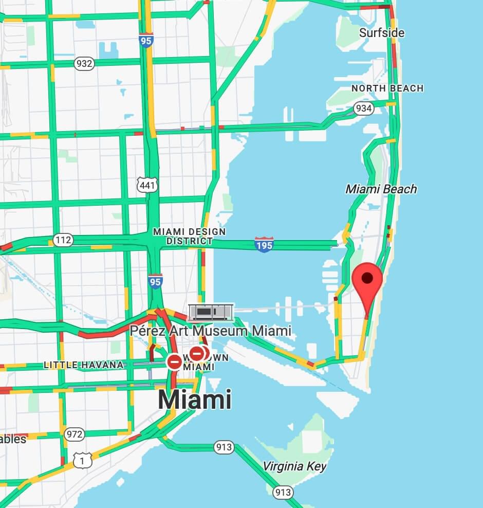 A wide-angle, behind-the-scenes view of a high-end film studio set where Rudy Mawer is seated in a director's chair. The shot shows professional cameras, studio lighting, and a large monitor displaying a close-up of him speaking.